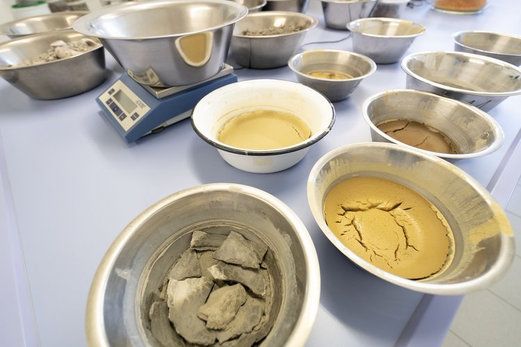 Verschiedene Metallnäpfe mit unterschiedlichen Arten und Farben von Ton oder Erde im bodenmechanischen Labor von GHB Consult.